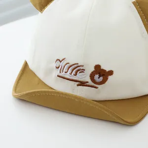 Gros plan sur la broderie ours et les oreilles 3D d'une casquette en coton pour bébé