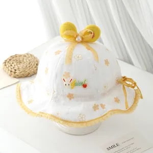 Détail du chapeau de soleil bébé avec broderie en dentelle, nœud jaune et oreilles de lapin