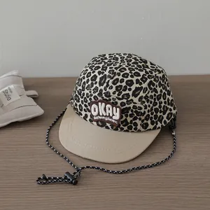 Detail of leopard print five-panel cap with flat brim and adjustable chin cord strap