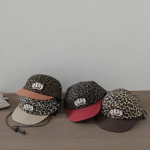 Detail of children leopard print baseball caps with OKAY embroidery and chin straps