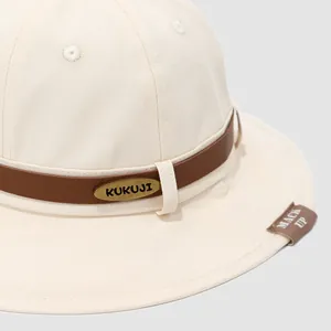 Canvas kids bucket hat in cream white featuring brown leather trim and metal detail