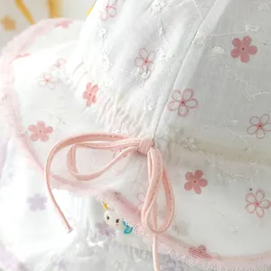 Détail du chapeau bébé avec broderie florale, bordure en dentelle rose et nœud