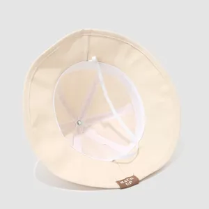 Detail view of beige baby sun hat with adjustable chin strap and soft cotton lining