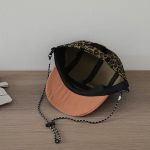 Detail view of leopard print hat with orange flat brim and adjustable windproof rope