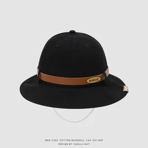 Detail of black cotton bucket hat showing brown leather strap and gold logo emblem
