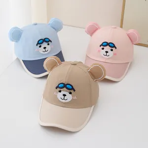 Three kids cartoon baseball caps with bear ears and goggles in blue, pink and khaki
