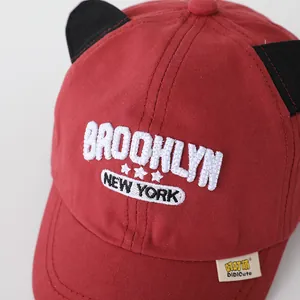 Close-up of red baseball cap with black cat ears and white Brooklyn embroidery