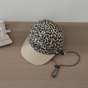 Detail of leopard print 5-panel hat with cream leather logo and woven chin strap
