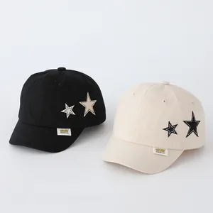 Detail of star embroidery and woven label on toddlers baseball caps in black and beige
