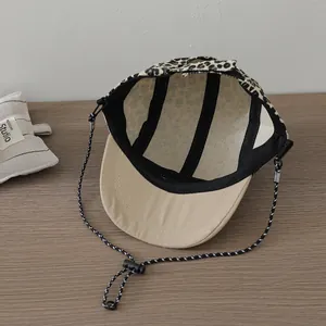 Detail of five-panel leopard print kids cap with adjustable drawstring and beige brim