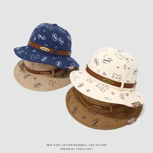 Détail de bobs en coton pour enfants montrant l'imprimé ours et le logo KUKUJI en métal