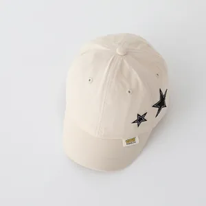 Close-up of beige kids baseball cap featuring star embroidery and a stitched brand label