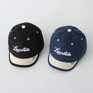 Detail of Leonikita script embroidery on contrast short-brimmed baseball caps for kids