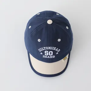 Detail of baby baseball cap with navy blue crown, beige brim and white Hilton Head embroidery