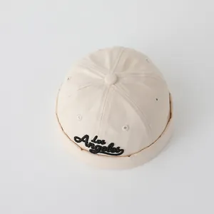Detail of beige cotton baby beanie featuring black Los Angeles cursive embroidery