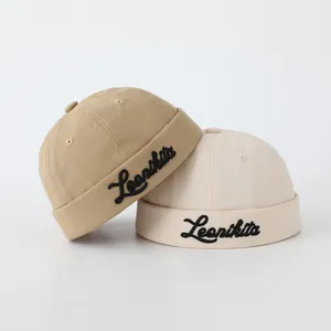 Vista detallada de los gorros docker caqui y crema con bordado cursivo de Leonikita