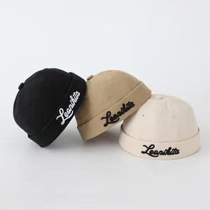 Detalle de gorros docker para niños en negro, caqui y beige con bordado en el lateral