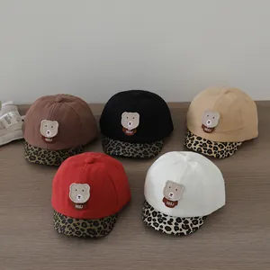 Detail of infant baseball caps with leopard print brim and plush bear patches in five colors