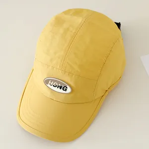 Detail van gele camper pet met zwart HONG-logo en verstelbare plastic sluiting aan de achterkant