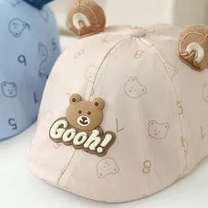 Detailed close-up of beige baby baseball cap featuring cute plush bear ears and rubber badge