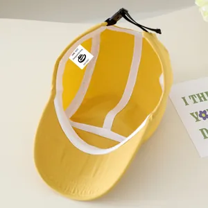 Detail van de binnenkant van een gele kinderhonkbalpet met verstelbare riem en logo