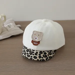 Detail of baby baseball cap with teddy bear patch and leopard print brim on wood