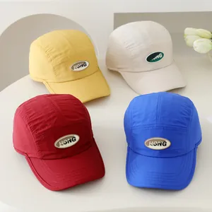 Detail van vier kleurrijke five-panel kinderhonkbalpetten met een HONG-letterpatch op rij