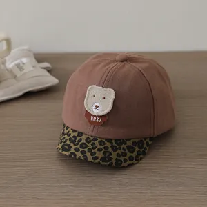 Detail of baby baseball cap with plush bear patch, leopard brim and suede texture