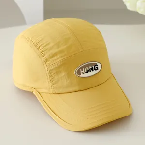 Detail van gele nylon baseballcap met HONG-letterpatch en fijne stikselafwerking