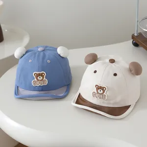 Detail of cute baby baseball caps with bear embroidery and 3D ears in blue and beige