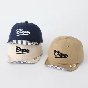Close-up of soft cotton baby baseball caps with Clape embroidery and striped brim detail