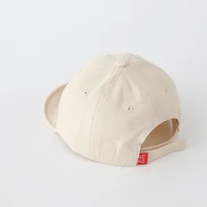 Dettaglio del cappellino da neonato in cotone beige con cinturino in velcro regolabile