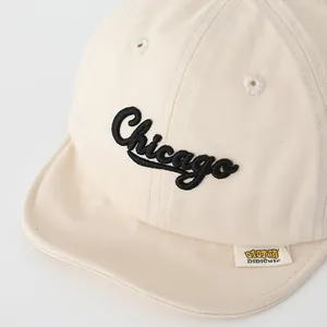 Dettaglio del cappellino beige per neonati con ricamo Chicago e trama in cotone premium