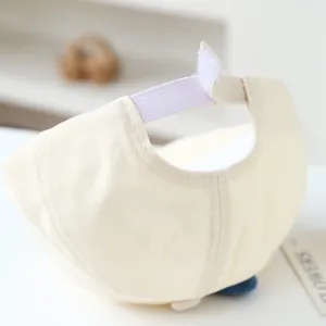 Detail of adjustable velcro strap on cream baby cotton cap with smooth stitching