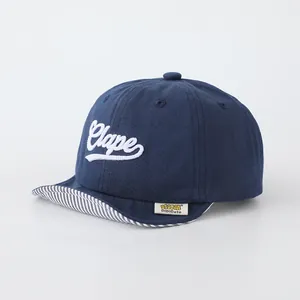 Detail of baby soft brim baseball cap featuring Clape embroidery and striped visor underside