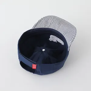 Detail view of navy baby baseball cap with striped brim and Di Di Cute label