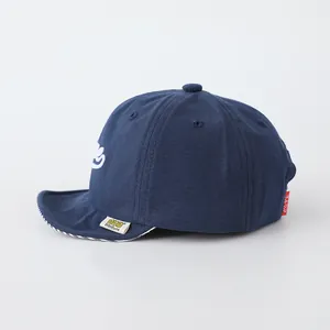 Detail view of navy baby baseball cap with striped brim and yellow brand labels