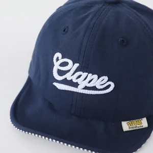 Detail of navy cotton baby baseball cap with white Clape embroidery and plaid brim edge