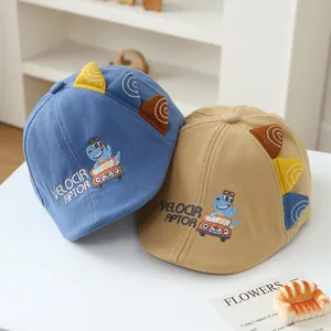 Detail of baby dinosaur cotton caps in blue and khaki with 3D fins and embroidery