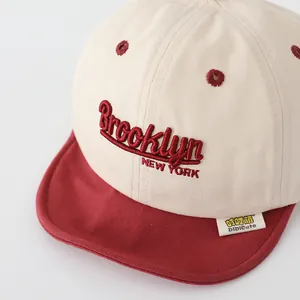 Detail of Brooklyn embroidery on cream canvas baby cap with a contrast red brim