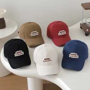 Detailed view of kids baseball caps in five colors with BAD BUSINESS embroidery on a white table