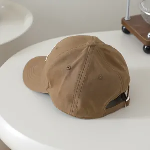 Detail of adjustable strap and metal buckle on the back of the brown cotton baseball cap