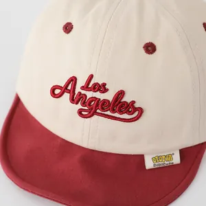 Detail of red Los Angeles embroidery on beige children's baseball cap with brand tag
