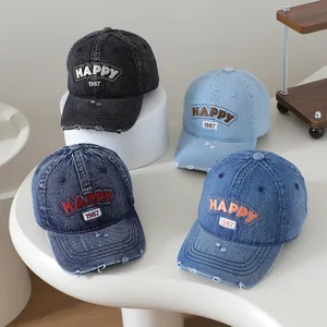 Détail de casquettes en denim vieilli avec broderie Happy 1987 et bords effilochés