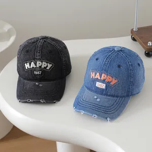 Gros plan sur des casquettes en jean délavé vintage avec broderie Happy 1987 et déchirures