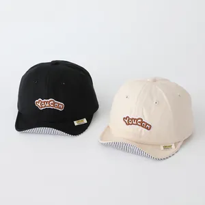 Detail view of cotton baby baseball caps with YouCan embroidery and striped brim lining