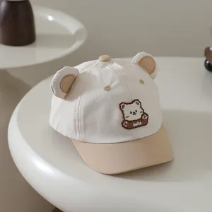 Detail von süßen Bärenohren und Hello-Stickerei auf einer beigen Baby-Mütze
