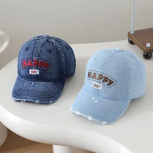 Détail de casquettes en jean délavé avec broderie Happy et texture de visière usée