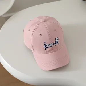 Detailed close-up of pink cotton baseball cap with blue Insbobo bear embroidery