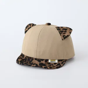 Detailed close-up of khaki baby baseball cap featuring leopard print ears and logo tag